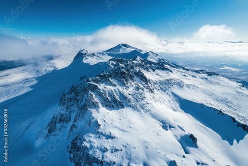 Majestic snow-capped mountain peaks under a clear blue sky with scattered clouds at sunrise