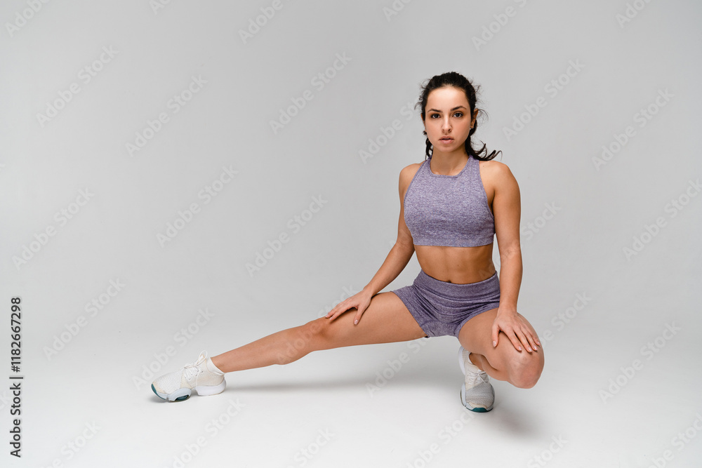 Full size strong sporty athletic fitness trainer woman in sportswear uniform spend time in home gym train exercising do workout sport stretch legs squat exercise isolated on white light background.