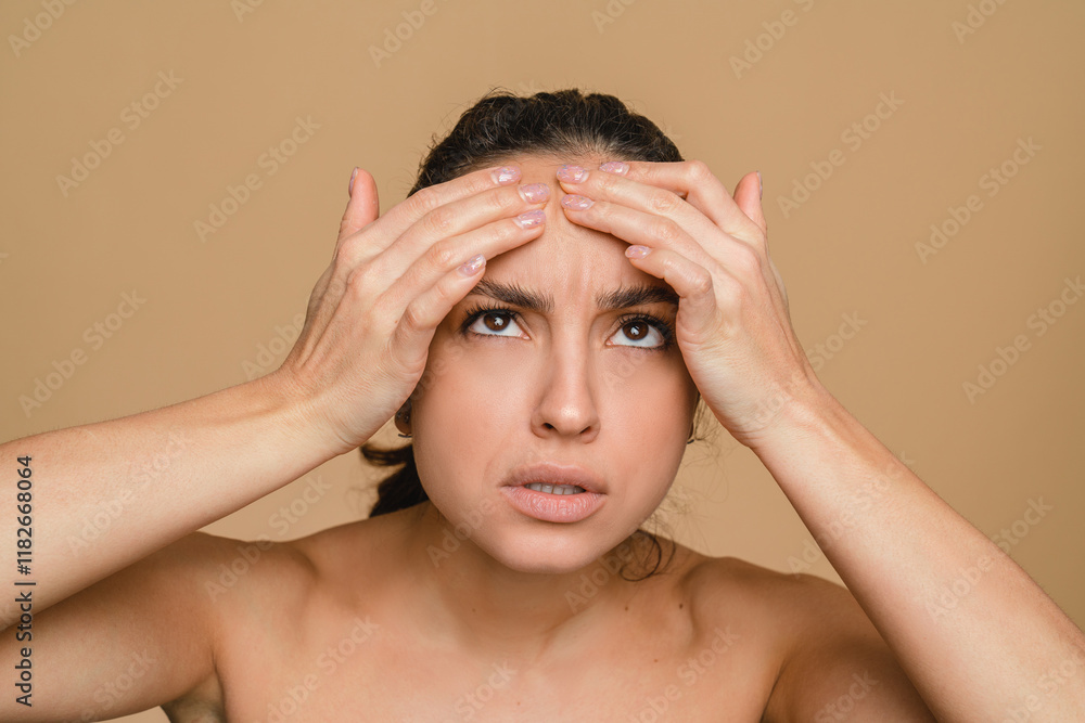 Acne pimples on face skin. Young hispanic sad woman looking for wrinkles on her face isolated in beige background. Anti-age cosmetics care treatment. Health dermatology skin problem. Acne pimples on face skin. Young hispanic sad woman looking for wrinkles on her face isolated in beige background. Anti-age cosmetics care treatment. Health dermatology skin problem.