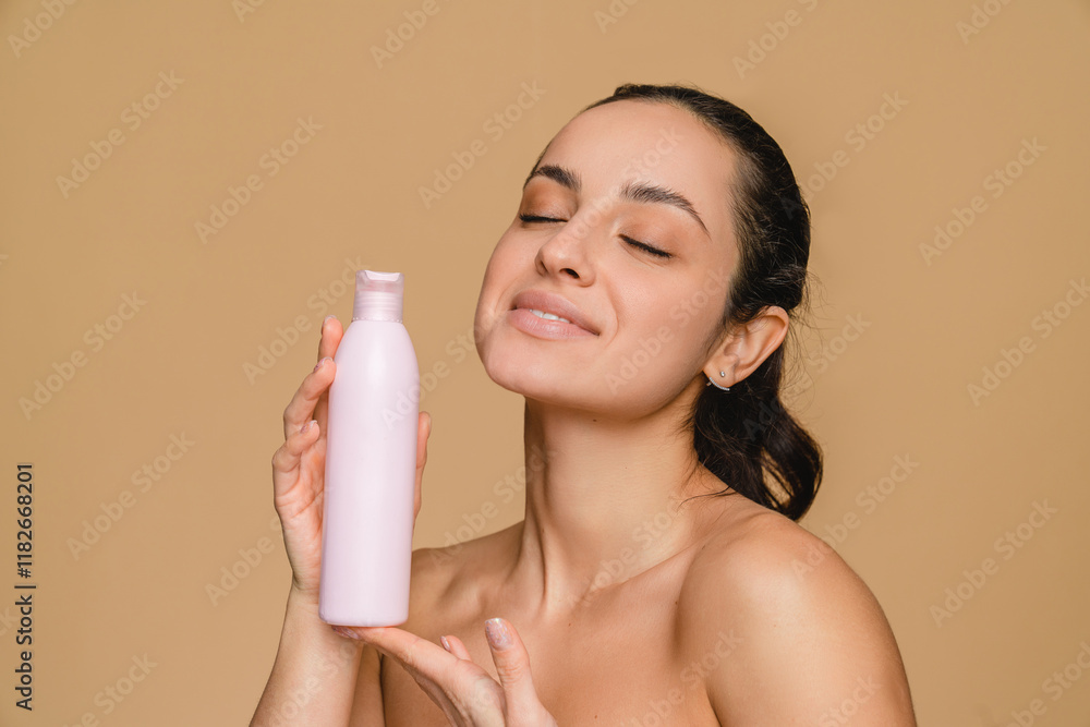 Smiling young hispanic latin woman lady girl closed eyes pointing at beauty treatment bottle product, shower gel hair shampoo face skin care, hydration and rejuvenation isolated in beige background Smiling young hispanic latin woman lady girl closed eyes pointing at beauty treatment bottle product, shower gel hair shampoo face skin care, hydration and rejuvenation isolated in beige background