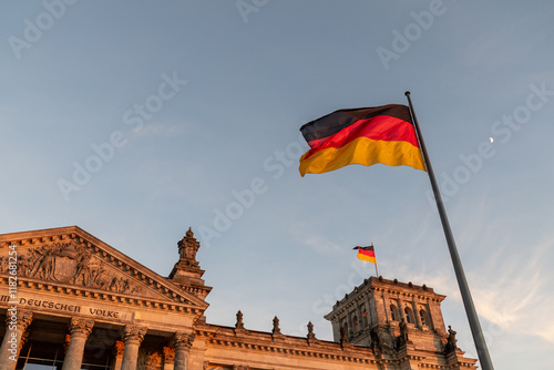 A pair of German flags flying in front of and on top of the Reichstag in Berlin
