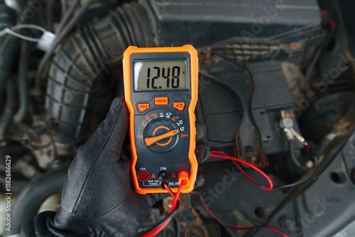 Obraz na płótnie Test car battery with multimeter in cold season. Checking car battery voltage with multimeter while ignition is off, diagnostics for reliable automotive performance in winter season w salonie
