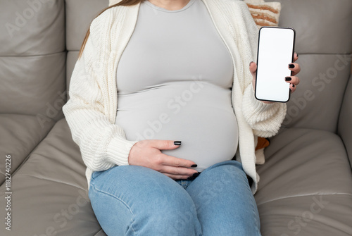 Konstfotografi Close-up of pregnant woman holding and showing mobile phone with empty display at home