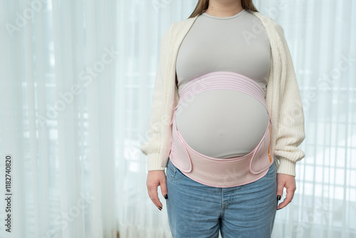 Canvas-taulu Pregnant woman adjusting a supportive maternity belt, copy space