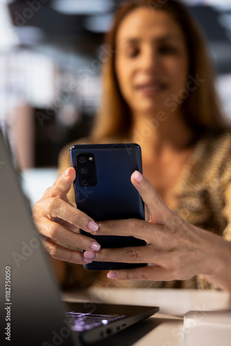 Business executive uses her mobile phone for research at office desk, finding solutions to overcome challenges while managing administrative tasks. Woman using smartphone on a break. Free Download Business executive uses her mobile phone for research at office desk, finding solutions to overcome challenges while managing administrative tasks. Woman using smartphone on a break. - GFXLoad