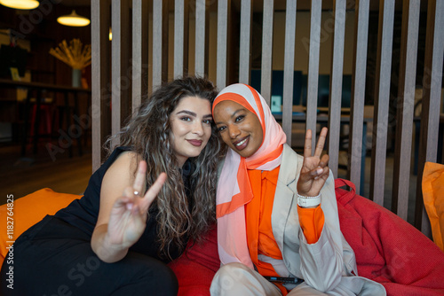 Two female friends of diverse background sitting and embracing  photo