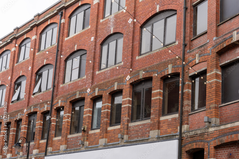 Obraz premium Brick building exterior wall with rows of windows and earthquake-strengthening plates