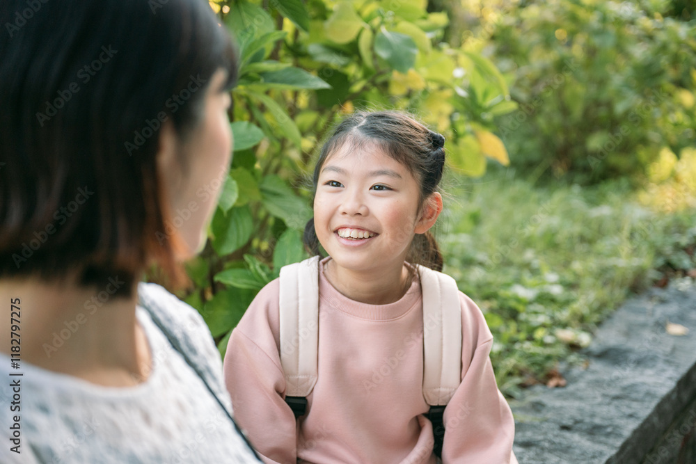 Smiling asian pupil chatting with her mother in a park Smiling asian pupil chatting with her mother in a park