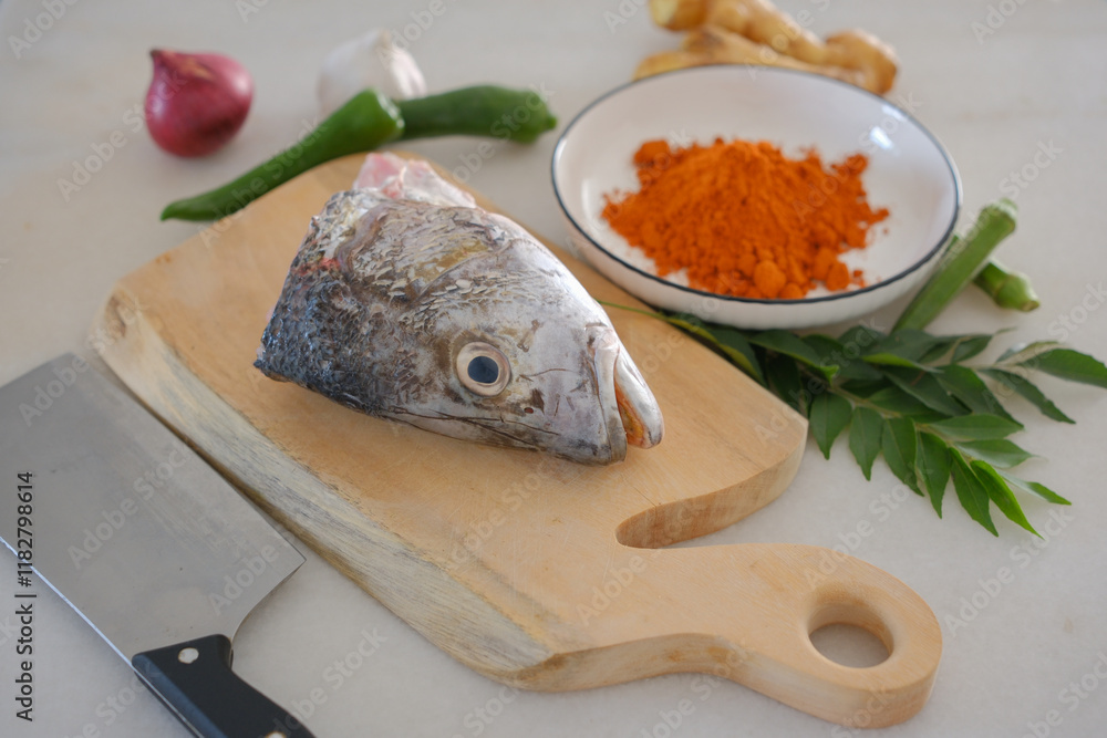 Fresh snapper fish on a wooden cutting board in a kitchen with a knife nearby
