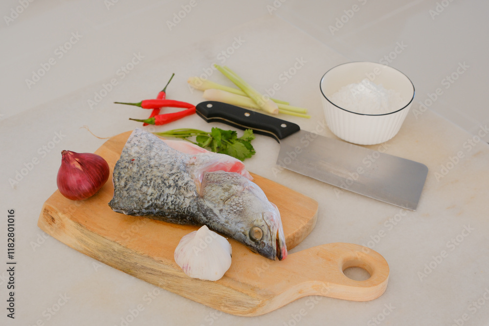 Fresh snapper fish on a wooden cutting board in a kitchen with a knife nearby
