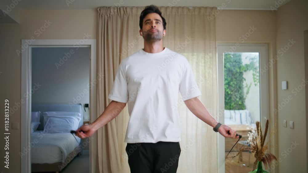 Man performing jump rope workout in modern apartment closeup. Energetic guy Man performing jump rope workout in modern apartment closeup. Energetic guy