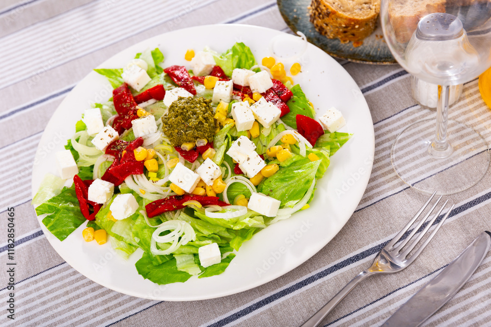 Delicious salad of fresh vegetables with corn, peppers, feta and pesto sauce on plate Delicious salad of fresh vegetables with corn, peppers, feta and pesto sauce on plate