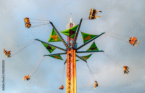 A colorful amusement ride swings people high above the ground at a county carnival fair
