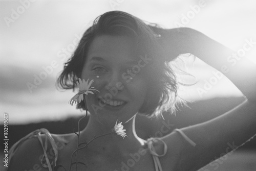 A portrait of a cheerful young woman holding a daisy photo