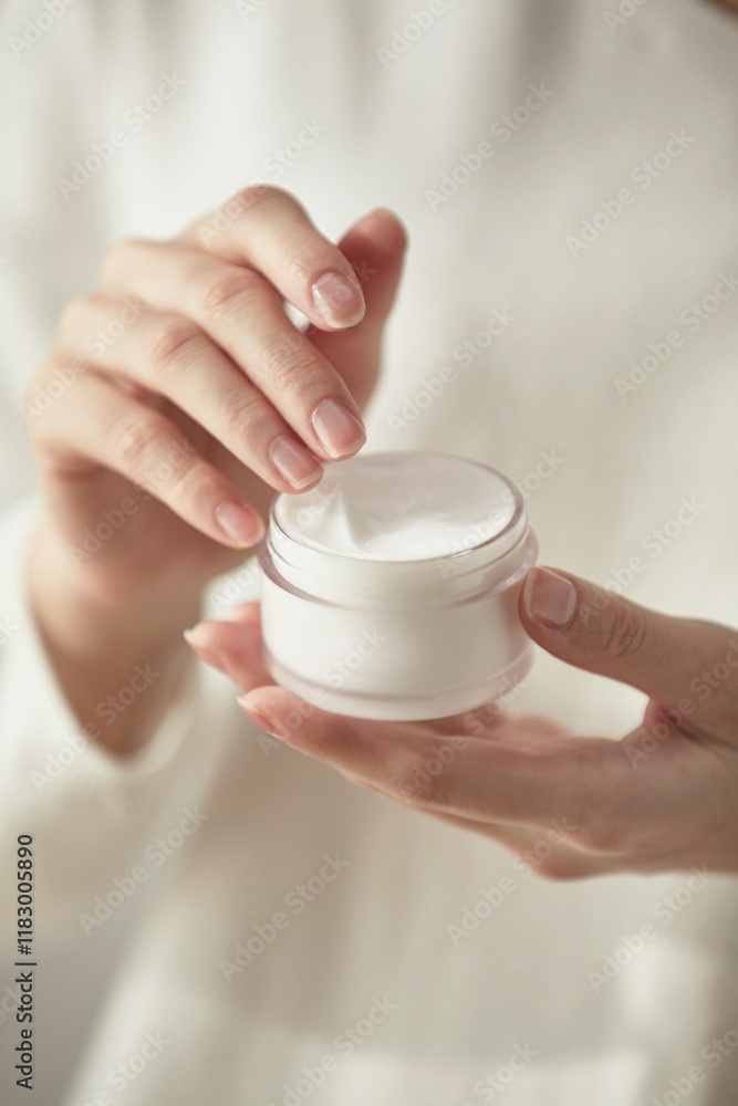 a woman holding cosmetics by a window in the sun a woman holding cosmetics by a window in the sun