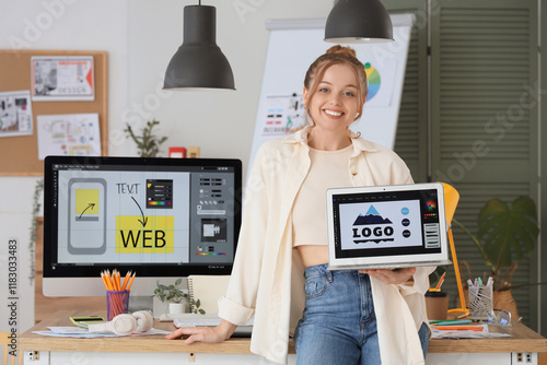 Female web designer with laptop near table in office