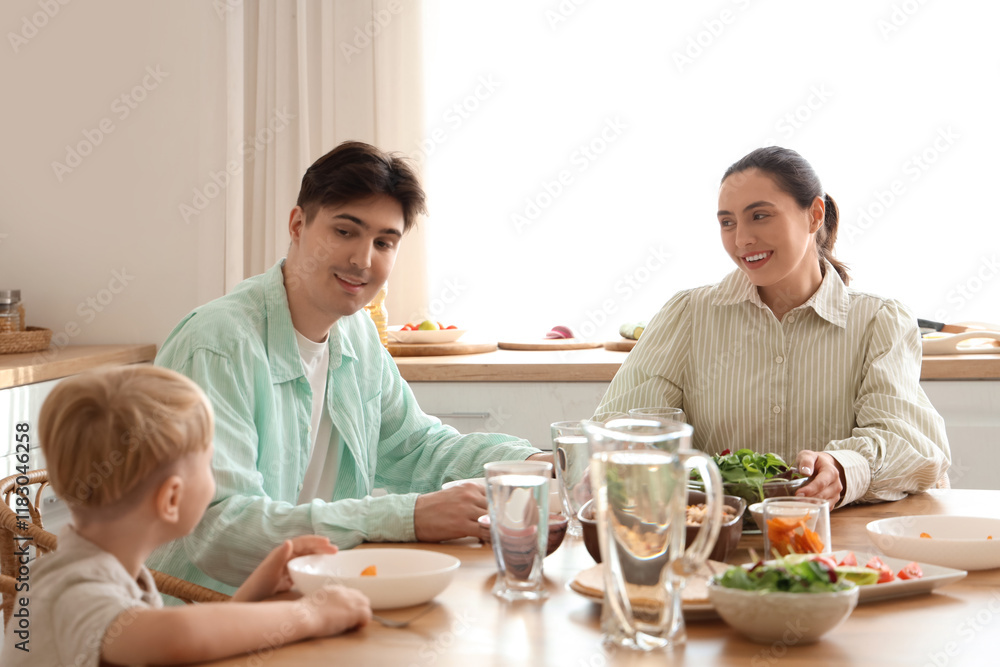 Parents with their little son eating Fajita at table in kitchen Parents with their little son eating Fajita at table in kitchen