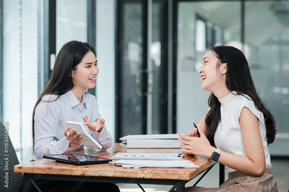 Two women in a modern office setting discussing business strategies with digital devices, showcasing teamwork and collaboration. Two women in a modern office setting discussing business strategies with digital devices, showcasing teamwork and collaboration.