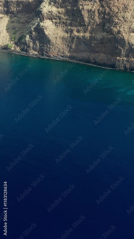 A stunning aerial view of steep rocky cliffs descending into deep blue ocean waters, capturing the natural beauty of Captain Cook, Hawaii.