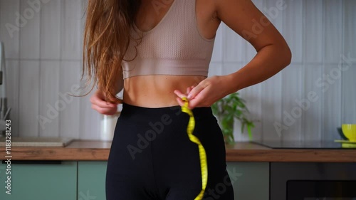Thin girl measuring her waist size with a tape measure, weight loss and slimming