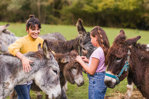 Woman and girl petting donkeys in animal sanctuary in quiros, asturias, spain