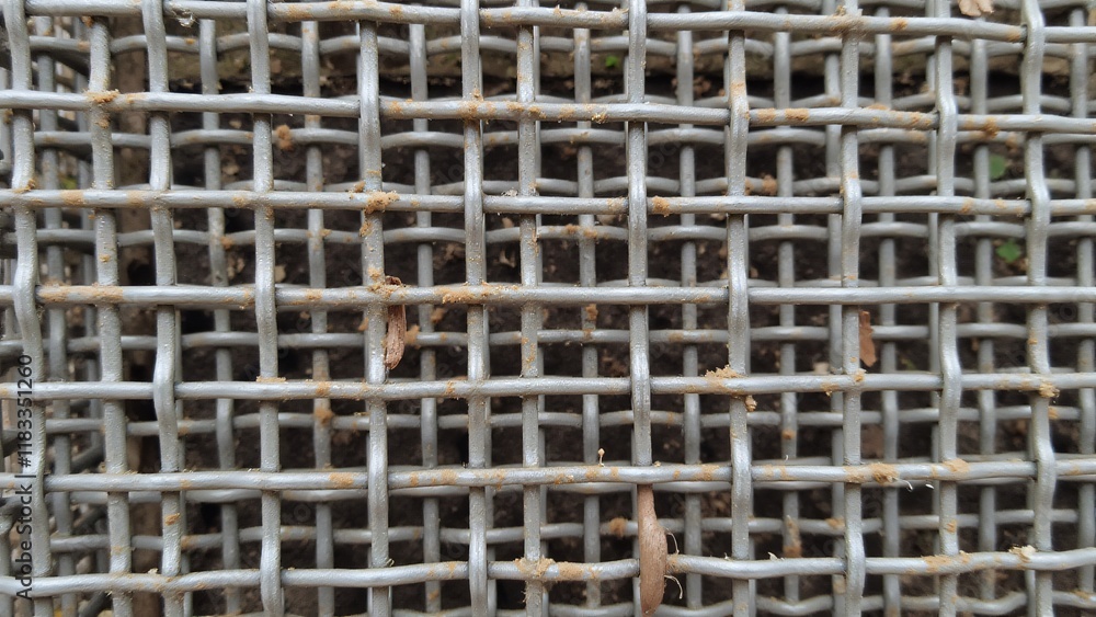 Worn metal grid surface, with dulled bars and rounded intersections showing signs of corrosion and stress, creating a rough, aged texture. Worn metal grid surface, with dulled bars and rounded intersections showing signs of corrosion and stress, creating a rough, aged texture.