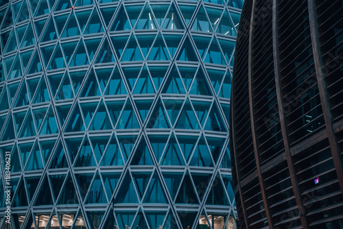 Geometric Facade: A close-up shot of a modern glass and steel skyscraper with a mesmerizing geometric pattern of triangles. The intricate design, reminiscent of a tessellated artwork.