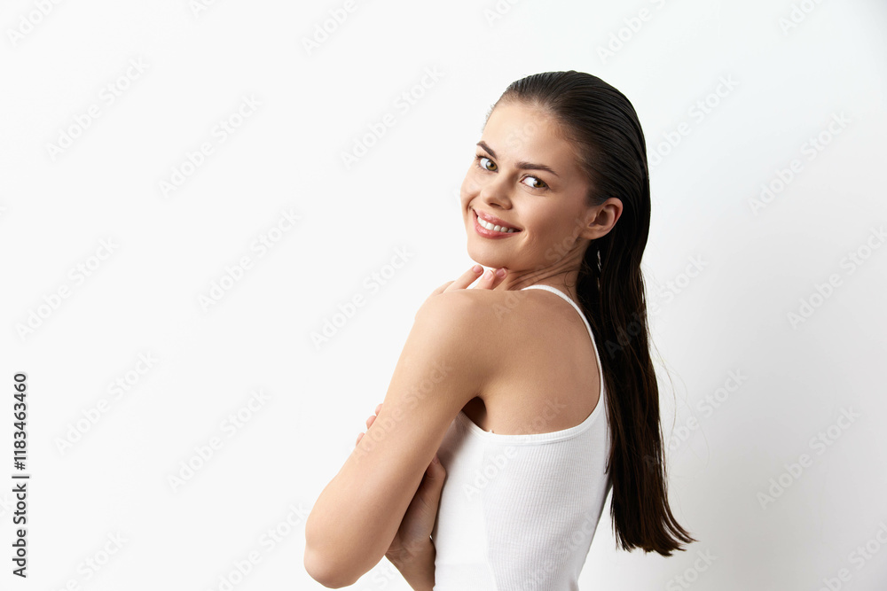 Smiling young woman with long hair showcasing confidence against a clean white background, wearing a simple white tank top, emphasizing natural beauty and self assurance Smiling young woman with long hair showcasing confidence against a clean white background, wearing a simple white tank top, emphasizing natural beauty and self assurance