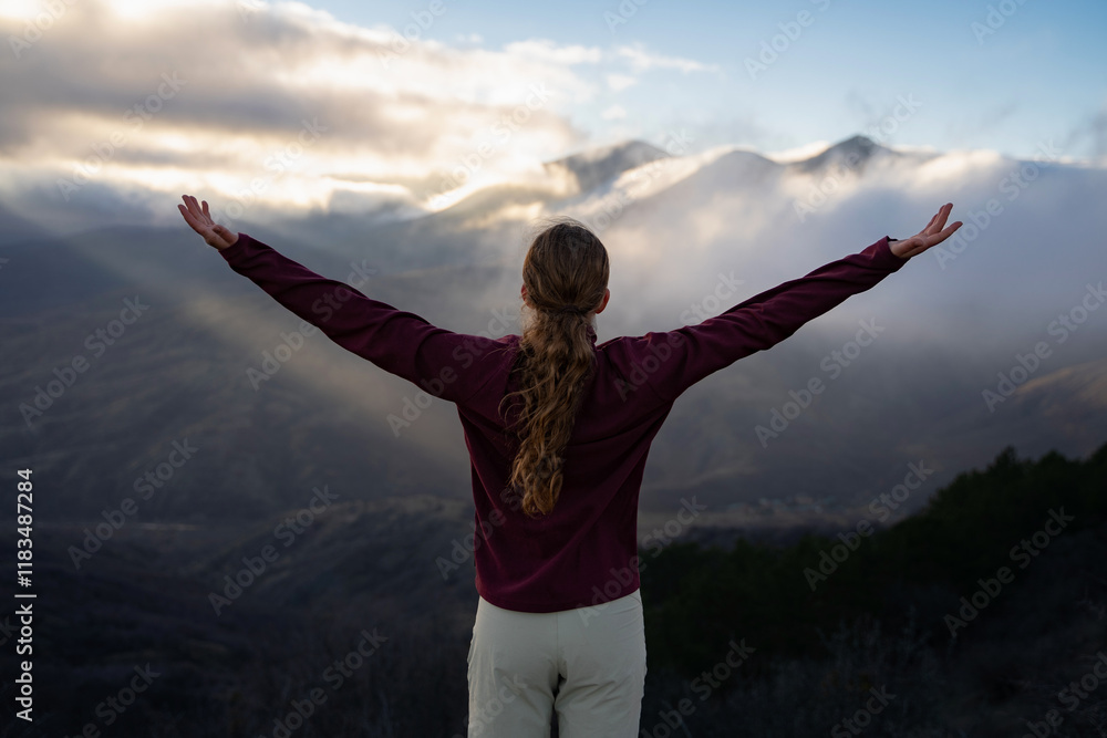 Hiker woman raising her hands up on the top of a mountain. Female traveler with hands up standing against the sunset in the mountains. Girl enjoying success and freedom outdoors. Travel tourism hiking Hiker woman raising her hands up on the top of a mountain. Female traveler with hands up standing against the sunset in the mountains. Girl enjoying success and freedom outdoors. Travel tourism hiking