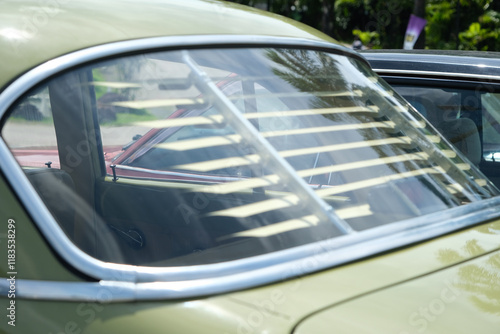 A close-up of a classic car’s rear window featuring vintage sunshade louvers. The chrome detailing and reflections enhance the nostalgic, retro, and timeless automotive appeal.