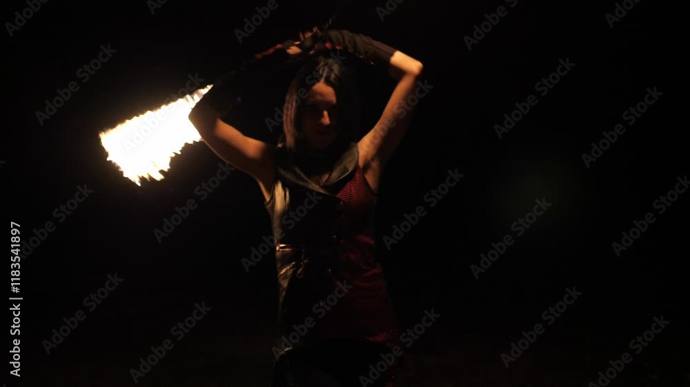 Close-up of a professional woman performing a fiery trick with a burning rope, spinning burning ropes in a circle on a black background. Close-up of a professional woman performing a fiery trick with a burning rope, spinning burning ropes in a circle on a black background.
