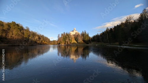 Beautiful winter scenery of Trakošćan Castle on the hill by the lake in the forest at Croatia, county hrvatsko zagorje, nature background photo