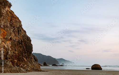 Coastal cliffside with a serene ocean and misty horizon at dusk photo