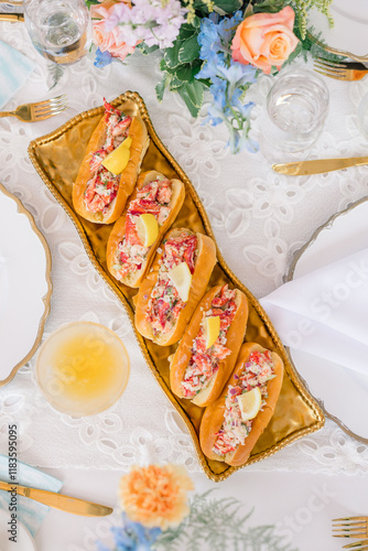 Elegant table setting with lobster rolls served on a golden platter. photo