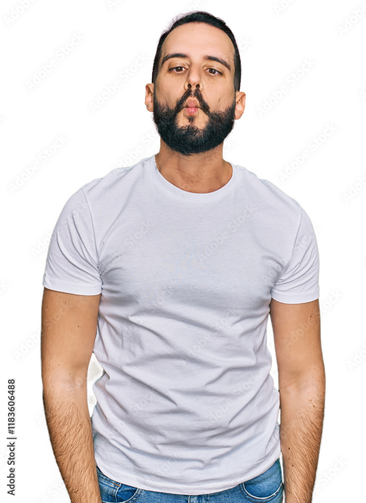 Young man with beard wearing casual white t shirt making fish face with lips, crazy and comical gesture. funny expression. Young man with beard wearing casual white t shirt making fish face with lips, crazy and comical gesture. funny expression.