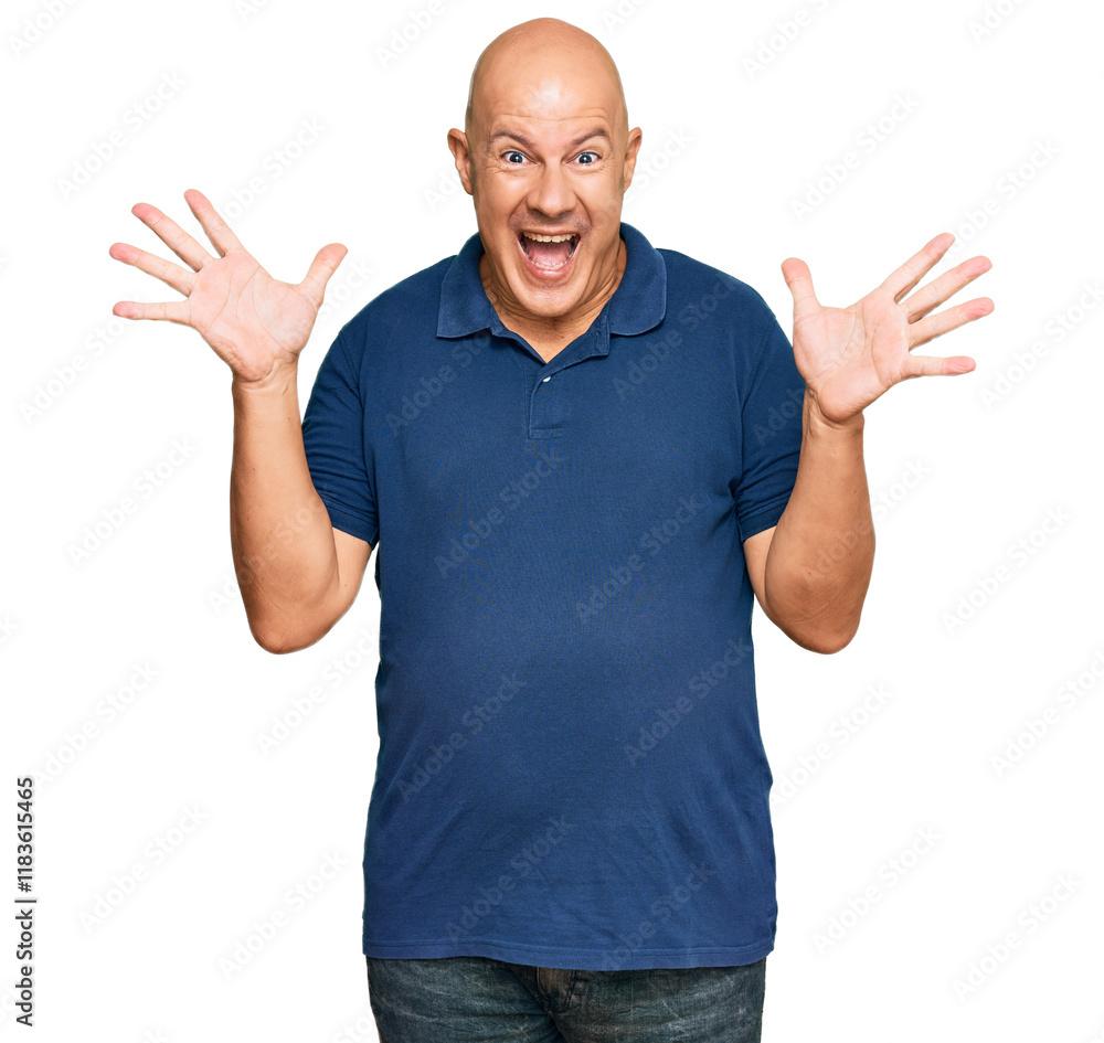 Fototapeta premium Middle age bald man wearing casual clothes celebrating crazy and amazed for success with arms raised and open eyes screaming excited. winner concept