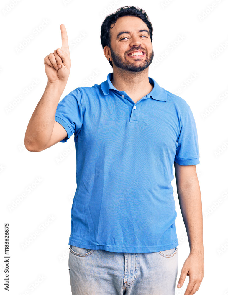 Young hispanic man wearing casual clothes showing and pointing up with finger number one while smiling confident and happy. Young hispanic man wearing casual clothes showing and pointing up with finger number one while smiling confident and happy.