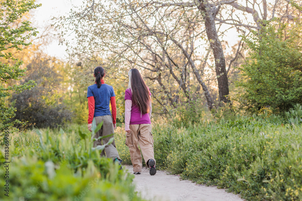 Two female hikers walking in nature on dirt path