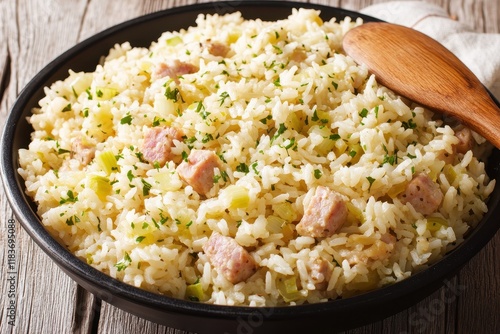 Close up of South American dish chicken bog or pilaf featuring rice smoked sausage and leek baked in broth served in a black bowl with a wooden spoon vertical s photo