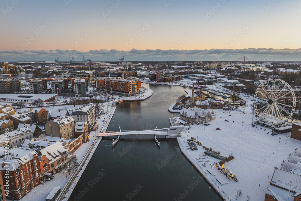 Obraz premium Gdańsk with a view of the Motława River in the morning in winter. Snow on the roofs of tenement houses and streets.