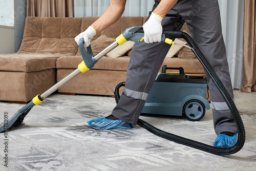A cleaner in special attire using a vacuum in a large living room, with elegant furniture and a bright atmosphere, showcasing professional cleaning services.