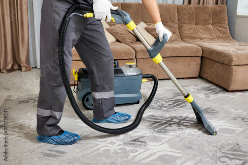 A professional worker in safety gear meticulously cleans a carpet using a powerful vacuum cleaner. The worker's expertise is evident in the thorough and detailed cleaning process.
