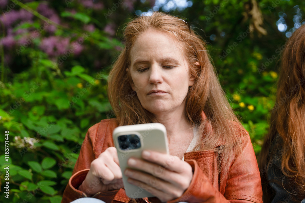 Woman using smartphone outdoors among greenery in a natural setting Woman using smartphone outdoors among greenery in a natural setting