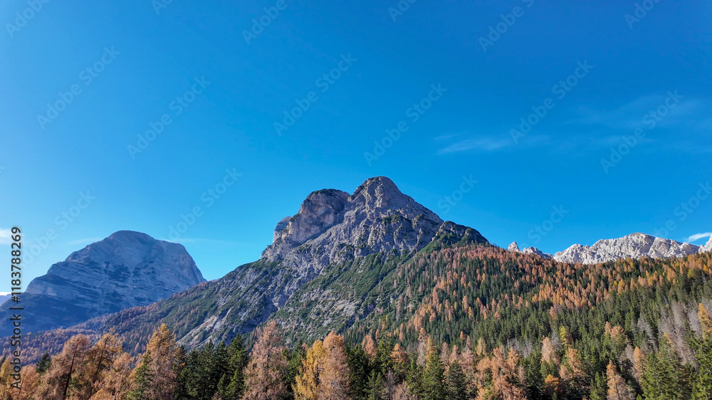 Majestic mountain range under a clear blue sky in autumn, symbolizing adventure and exploration during the fall season Majestic mountain range under a clear blue sky in autumn, symbolizing adventure and exploration during the fall season