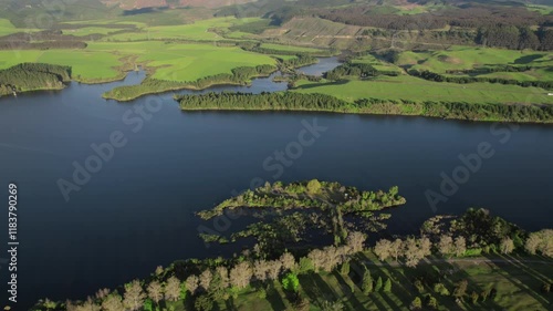 Peaceful aerial view of a vast lake bordered by lush greenery, forests, and rolling hills. photo