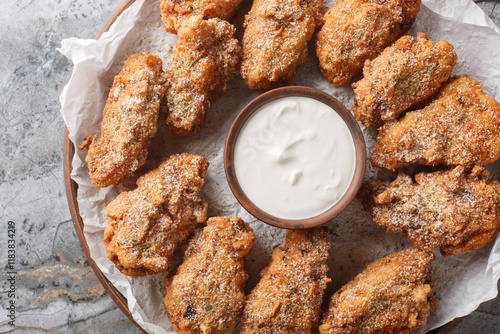 Korean fried chicken in cheese garlic onion breading with dipping sauce close-up in a plate on the table. Horizontal top view from above photo