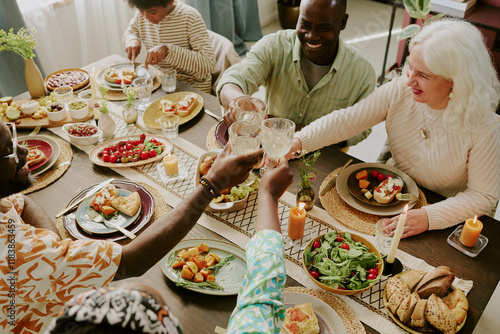 Tableau sur toile High angle shot of biracial family clinking glasses with champagne while enjoyin