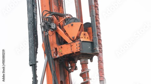 Heavy machinery pile auger rig drills into ground at construction site in urban environment