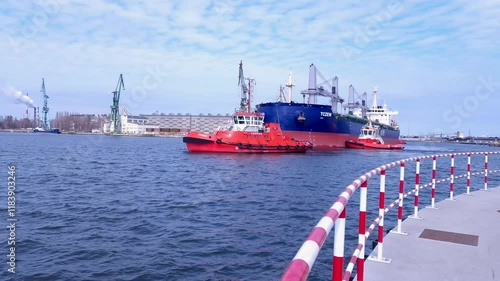 04 09 2023 Tugboats assist large cargo ship navigating through busy harbor waters. Baltic Sea, Gdansk, Poland photo