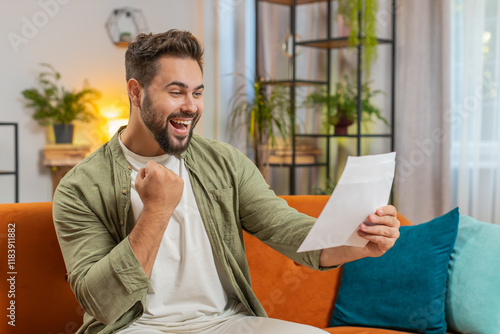 Happy man with brown hair open envelope letter, reading it. Career growth advance promotion, bank loan approve, successful admission to university monetary award invitation great news, lottery win. photo